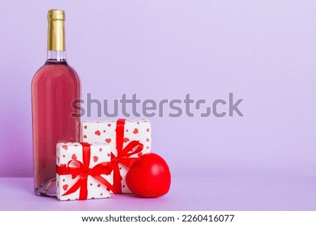 Bottle of wine on colored background for Valentine Day with gift box. Heart shaped with presrnt box perspective view with copy space.