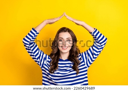 Photo portrait of pretty young girl raise arms show roof safe protection wear trendy striped clothes isolated on yellow color background