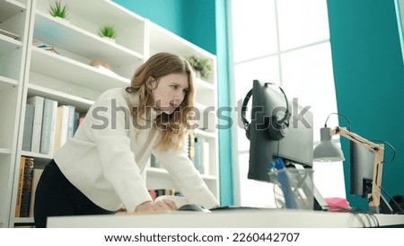 Young blonde woman student using computer studying at library university