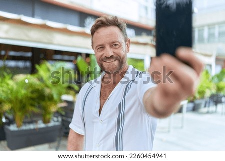 Middle age man smiling confident making selfie by the smartphone at coffee shop terrace
