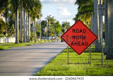 Road work ahead sign on street site as warning to cars about construction and utility works