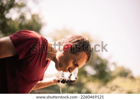 Man farmer pouring water on himself standing in the garden during summer heat Royalty-Free Stock Photo #2260469121