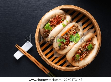 Food concept Homemade organic Pulled Beef Bao Buns or Gua Bao in bamboo stream tray on black background with copy space Royalty-Free Stock Photo #2260473167