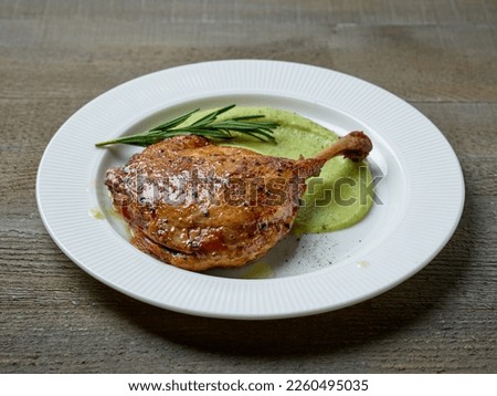 duck leg confit and broccoli puree on white plate