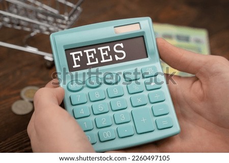 calculator with the inscription FEES is placed in the stack of documents. Business concept.
