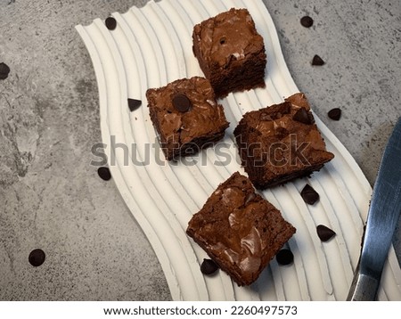 Detail of four pieces of bandung brownies on a white aesthetic wave tray with a gray concrete background. Close up food photography