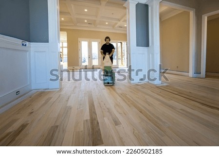 Carpenter grinding a wooden parquet floor by using floor sander in newly constructed house to ensure that it is smooth even Royalty-Free Stock Photo #2260502185