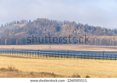 Photovoltaic solar cell panels against the backdrop of autumn forest in mountain. Renewable energy source. Solar power generation. Sustainable resources. Environmental theme.