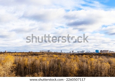 cloudy sky over forest and city on horizon on sunny autumn day