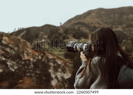 Woman photographer taking pictures with her camera in a part of the Andes mountain range in Peru. Concept professions, people, travels and vacations.