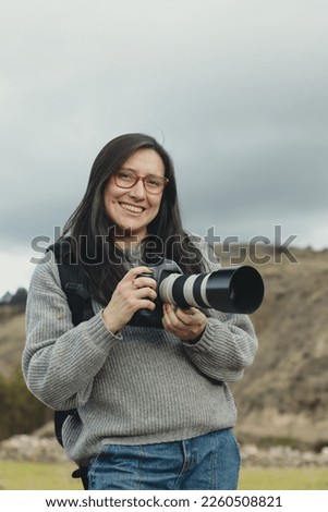Portrait of a woman photographer smiling with her camera in her hand in a part of the Andes mountain range in Peru. Concept professions, people, travels and vacations.