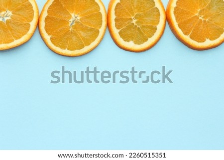 Orange slices at the top of the picture isolated on light blue background. Space for text.