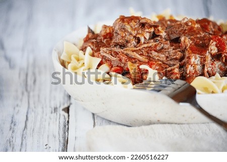 Hearty bowl of fresh homemade beef ragu over cooked egg noodle pasta. Extreme shallow depth of field with blurred foreground and background.