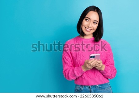 Photo of cheerful thai girl use telephone beaming smile look empty space isolated on blue color background