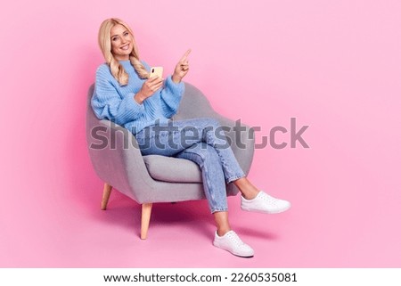 Photo of lovely glad lady wear stylish clothes sit chair demonstrate empty space modern technology isolated on pink color background