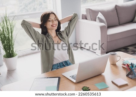 Photo of pretty calm lady sit comfort chair netbook home indoor success achieve growth career promotion enjoy relax rest hand behind head