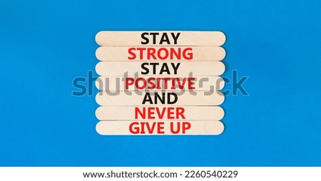 Never give up symbol. Concept words Stay strong stay positive never give up on wooden stick. Beautiful blue table blue background. Copy space. Motivational business never give up concept.