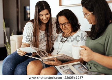 Three generation family looking at old photo album in living room.
