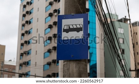 Public transport stop sign on a concrete pole. A blue and white rectangle with a picture of a bus.