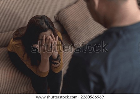 A fearful wife looks up to her abusive husband, afraid of being hit. Example of a victim in domestic abuse and physical violence in couples. Royalty-Free Stock Photo #2260566969