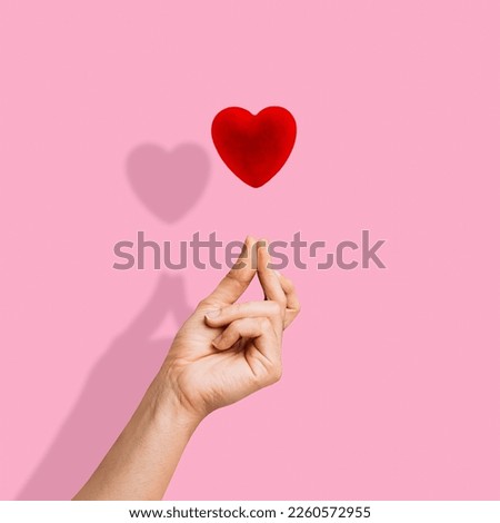 Trendy composition made of Korean love sign, Finger Snapping on pink background. Minimal concept of Valentine's Day or love. Korea finger heart. Creative art, minimal aesthetics.