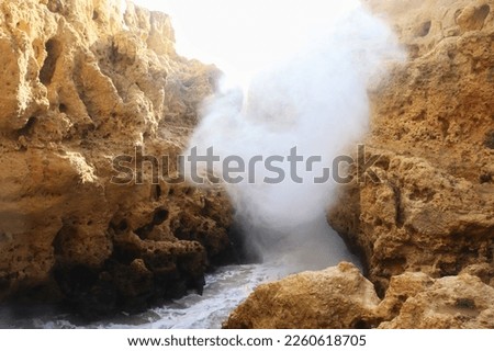 Water splashing over side of cliffs on a sunny winter day in Carvoeiro, Portugal.