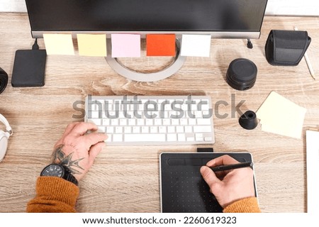Top view of hand holding stylus on graphic tablet for retouching work. A photographer using an editing application to touch up images in a photography studio.