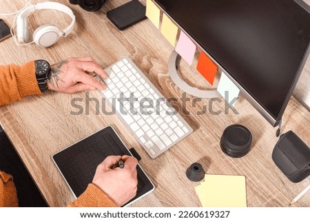Close up of hand holding stylus on graphics tablet for retouching work. A photographer using an editing application to touch up images in a photography studio.