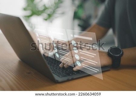 A worker types on a laptop keyboard into a document management system (DMS) or database, which is the concept of using technology to effectively manage files and document storage in digital format. Royalty-Free Stock Photo #2260634059