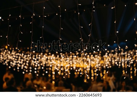 String led fairy lights in warm yellow tone at a party at night. Royalty-Free Stock Photo #2260645693