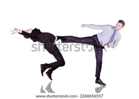 Businessman kicks the other businessman in a business suit - business competitor concept