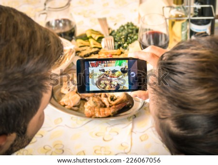 Couple of boyfriend and girlfriend taking a food selfie in dinner restaurant - Moda of catching the instant with modern smartphone at lunch meeting with typical italian food - Warm filter