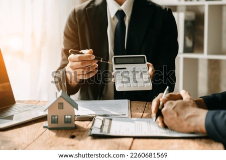 Real estate broker agent presenting and consult to customer to decision making sign insurance form agreement, home model, concerning mortgage loan offer i

