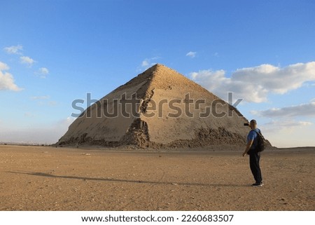 Pyramids of Dahshur. Bent Pyramid.Bent Pyramid. In the foreground, a tourist stands with his back and takes a photo on his phone