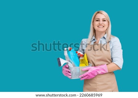 Photo of caucasian pretty housemaid wearing rubber gloves for hands protection holding bucket with cleaning supplies isolated over blue background