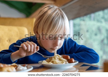 Fair-haired teenager at table eating pasta. Child boy is having lunch. Boy while eating. Student eating in the school cafeteria. Royalty-Free Stock Photo #2260704275