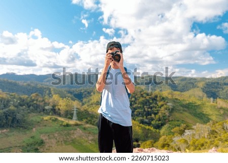 Traveler man on top of a mountain and taking pictures with his professional camera of the landscape.