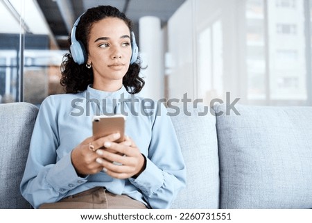 Music headphones, phone and business woman on sofa in office streaming audio. Cellphone, technology and thinking female employee on couch listening to podcast, radio or sound with mobile smartphone.