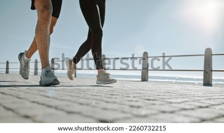 People, legs and running at the beach for exercise, cardio workout or training together outdoors. Leg of friends taking run, walk or jog on warm sunny day by the ocean coast for healthy wellness Royalty-Free Stock Photo #2260732215
