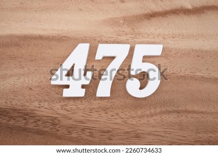White number 475 on a brown and light brown wooden background. Royalty-Free Stock Photo #2260734633