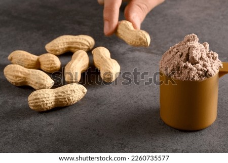 Choosing natural protein or protein powder, a male hand choosing peanuts instead of protein powder