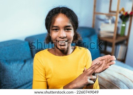 Beautiful smiling black deaf girl using sign language at home Royalty-Free Stock Photo #2260749049