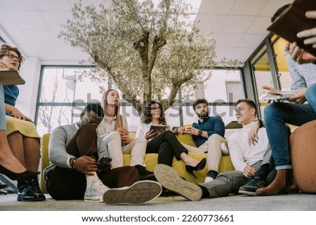 A low angle view photo of group of multicultural colleagues sitting and having a conversation at the office