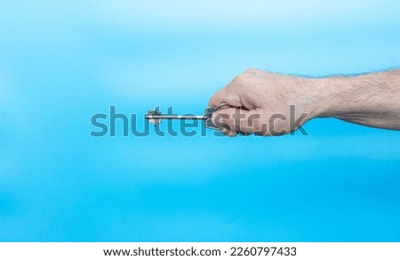 The elderly man has the key to the apartment in his hands. The concept of buying real estate. On a blue background. Security is the key. Copy space