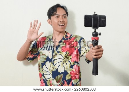 portrait of asian man holding smartphone or camera. Indonesian men's gestures are taking pictures, communicating, recording videos, video calls, or selfies. content creator illustration