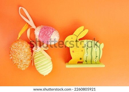 Easter wooden rabbit and decorated eggs on orange background. Easter celebration.