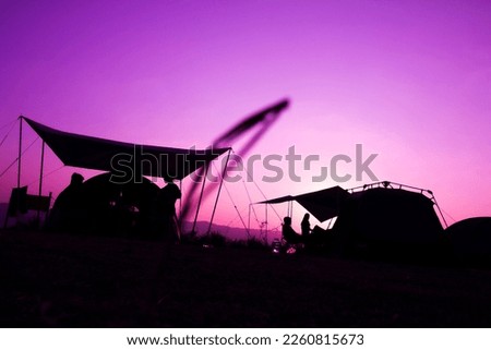 Silhouette on sunrise, a group of tourists or adventurers with tents