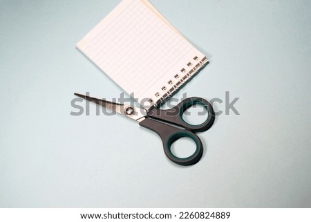 Notepad and scissors on a white isolated background