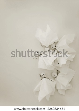 Candies turned into ghosts with paper napkins and black and white cord on a white background