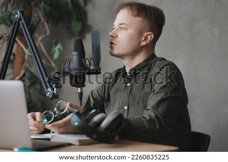 man in studio is recording podcast, audio content of interview on radio. Caucasian male speaks into microphone for voice recording or advertising. working online on internet, discussing acutely social